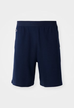 Navy blue shorts with a textured fabric, elastic waistband featuring raised logo, and a small embroidered emblem on the left leg.