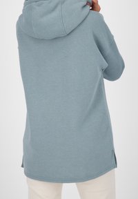 Huppari vaaleansinisenä, rento istuvuus, sivuaukot ja pehmeä pinta. Näkyvä ommel helmassa ja hihoissa.