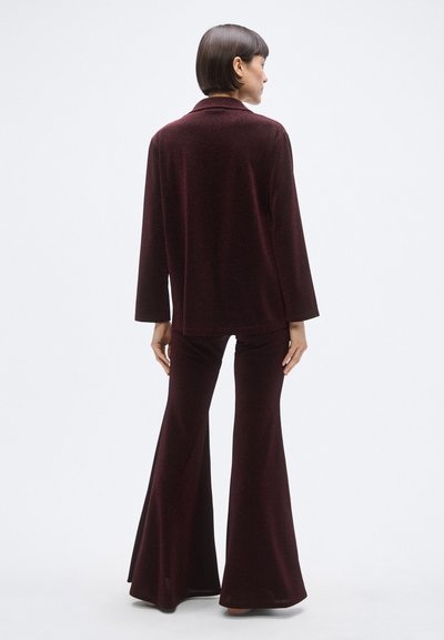 Vinrøde udvidede bukser og matchende langærmet top i blødt, tekstureret stof. Har reverskrave og afslappet pasform. Synligt sømdetalje bagpå.