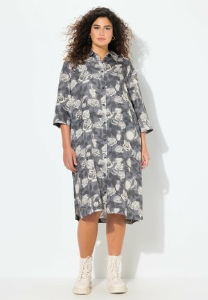 Blumenhemdkleid in Grau und Creme, mit Knopfleiste, Kragen, drei Viertelärmeln und knielangem Schnitt. Gestylt mit leichten Stiefeln.