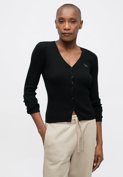 Cardigan negru cu tricot cu nervuri, de tip V, cu mâneci lungi și cinci nasturi pe față. Cu un logo mic și subtil pe piept.