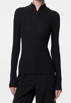 Dopasowany, czarny prążkowany top z długim rękawem, z subtelnym przednim szwem i małym stójkowym kołnierzem, zestawiony z czarnymi spodniami.