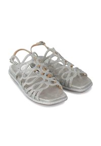 Srebrne sandały z misternym, wyciętym wzorem i błyszczącymi akcentami. Płaska podeszwa z miękką szarą wkładką oraz regulowanym paskiem na kostce.