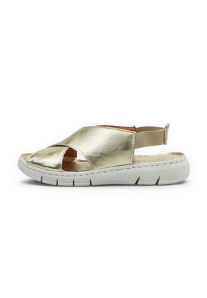 Sandalo dorato casual con cinturini incrociati, cinturino posteriore elastico e suola spessa in gomma bianca progettata per comfort e facilità d’uso.
