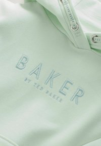 Mentolová mikina vyrobená z mäkkej tkaniny s vyšitým logom "BAKER" v svetlomodrej farbe. Obsahuje kovové prvky a šnúrky.
