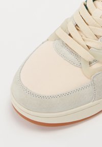 Beige vászon és szürke velúr sneaker texturált részletekkel, kerek orral és világos bézs fűzőkkel. Gumi talp barna részletekkel.
