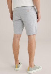 Mænds lysegrå stribede shorts med to baglommer og guldknapper, parret med grå sneakers med gul accent.