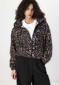 Cropped black and brown leopard print jacket made of soft material, featuring a high collar and zip closure. A casual design with a relaxed fit.