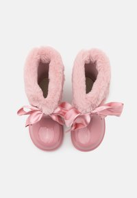 Bottes en fausse fourrure rose avec un extérieur en caoutchouc rose brillant. Présente des liens en satin et un design à bout rond. Intérieur doux et texturé.