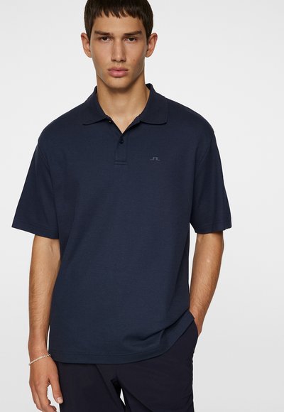 Marineblå kortærmet polo skjorte med krave og et diskret logo på brystet. Fremstillet af et glat, blødt stof med en afslappet pasform.