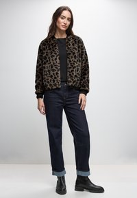Leopard print faux fur bomber jacket with black ribbed cuffs, paired with dark blue straight-leg jeans and black ankle boots.