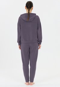 Lila hoodie och matchande joggers gjorda av mjukt material. Löst snitt med ribbade ärmslut och midja, med huva och inga framträdande detaljer.