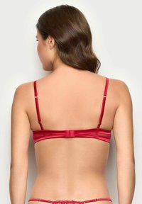 Sujetador de satén rojo con tirantes ajustables, cierre de gancho y ojos, y una textura suave, que exhibe un diseño minimalista sin adornos.