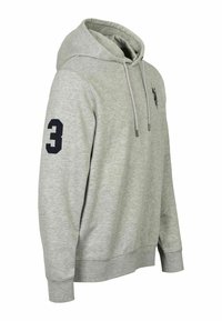 Sweat à capuche gris clair avec cordons, un écusson noir numéro trois sur la manche droite et un petit logo noir brodé sur la poitrine.