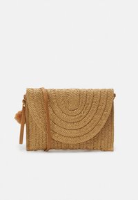 Tkanina torbica od slame u bež boji s zakrivljenim, teksturiranim uzorkom. Ima smeđi remen i ukrasni pompon sa strane.