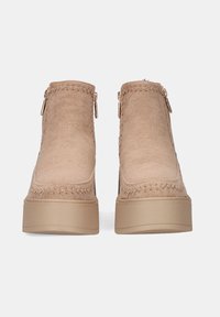 Botines beige con un upper suave y texturizado, costuras decorativas, cierres de cremallera a cada lado y una suela de plataforma chunky beige.