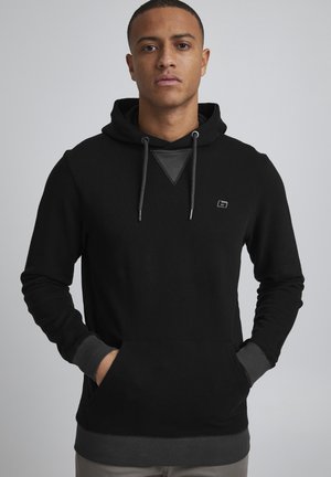 Sweat-shirt à capuche noir avec des manches longues, accents gris sur les poignets et la poche, ourlet côtelé, et un petit logo sur la poitrine.