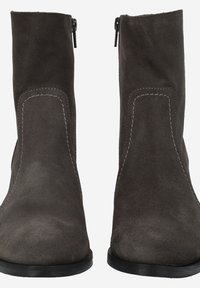 Bottines en daim gris avec une texture lisse, présentant des coutures blanches contrastantes, un bout rond et une fermeture éclair sur le côté.