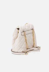 Cream quilted leather backpack with gold chain straps and adjustable leather shoulder strap against a white background.