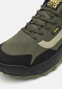 Vans MTE batai su alyvuogių žalios spalvos tekstiliniu viršumi, juodais akcentais, tekstūruota danga, sustiprintu toe ir storu juodu padu.