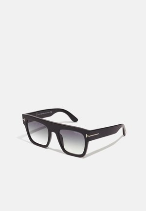 Óculos de sol quadrados pretos com lentes degradê, apresentando um acabamento fosco e detalhes em metal prateado na armação. Logótipo da marca visível no interior.