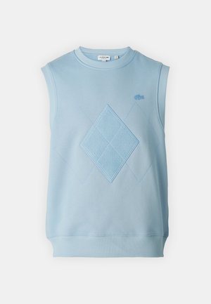 Svetlomodrý bezrukávový sveter s okrúhlym výstrihom. Má vzor vyšitých diamantov a ribbovaný spodný lem. Je viditeľné logo Lacoste.