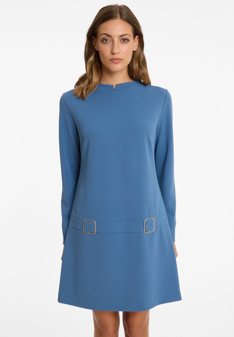 Blaues langärmliges Kleid mit rundem Ausschnitt, ausgestattet mit zwei goldenen quadratischen Akzenten in der Taillenregion und einer lockeren Silhouette. Weiche Textur.