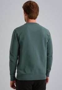 Mørkegrøn bomulds sweatshirt med rund halsudskæring, ribbede manchetter og et ensfarvet bagside-design. Har en glat tekstur og tætsiddende talje.