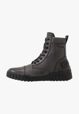 Schwarzer hochgeschnittener Lederstiefel mit dicker Gummisohle, Schnürverschluss und Markendetail an der Ferse.