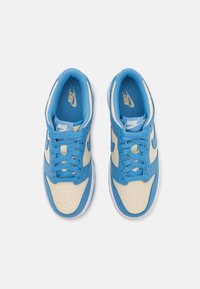Plave i krem boje Nike tenisice izrađene od kože i mrežastog materijala, s perforiranim vrhom, dvobojnim dizajnom i ravnim vezicama. Gumeni potplat.
