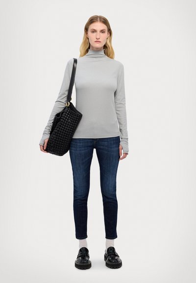 Heledad hallide turtleneck, tumepruunid teksad, must kootud käekott, mustad tossud paksude tallaga ja valged sokid. Lihtne disain.