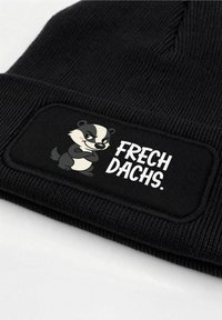 Black knit beanie featuring a textured band with a cartoon badger graphic and the text "FRECH DACHS." in white.