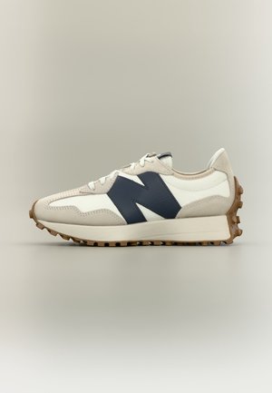 Biało-beżowy sneaker z ciemnoniebieskim logo "N", teksturowaną gumową podeszwą i białymi sznurowadłami, pokazany z lewej strony na jednolitym tle.