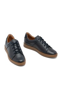 Modre usnjene športne čevlje z teksturirano površino, okroglim nosom, vezalnim sprednjim delom in rjavim gumijastim podplatom. Imajo minimalističen dizajn in kontrastne detajle.