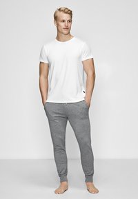 Hvid t-shirt med korte ærmer, parret med gr�å tætsiddende sweatpants, lavet af blødt stof, med ribbet tekstur og elastiske manchetter.