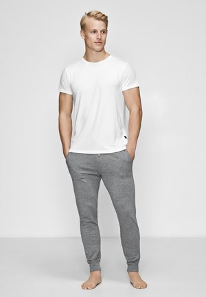 Hvid t-shirt med korte ærmer, parret med grå tætsiddende sweatpants, lavet af blødt stof, med ribbet tekstur og elastiske manchetter.