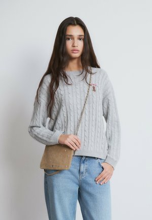 Suéter gris de punto con costuras en relieve y puños acanalados, combinado con jeans de talle alto en azul claro y un bolso de hombro beige con detalles de tachuelas.