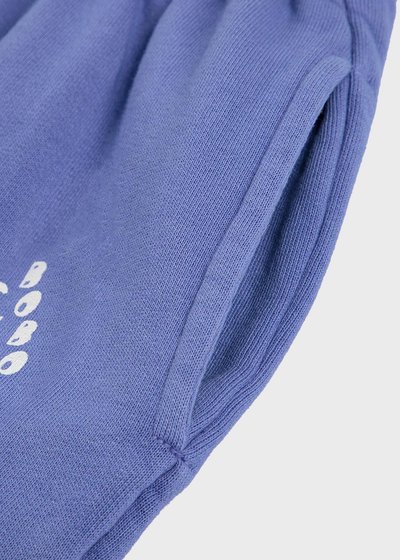 Lila stickad tröja med ribbad textur och sidoficka. Har vit tryckt text på framsidan. Tyget verkar mjukt och något elastiskt.