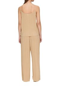 Beige geplooide mouwloze top met dunne bandjes, gecombineerd met bijpassende wijde broek met een zachte textuur en ontspannen pasvorm.
