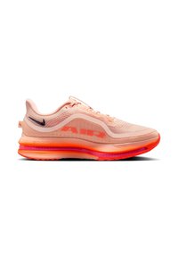 Zapatilla de running Nike Air Zoom en un ligero color coral-rosa con parte superior de malla, suela naranja neón y pequeño swoosh en azul marino oscuro en el talón.
