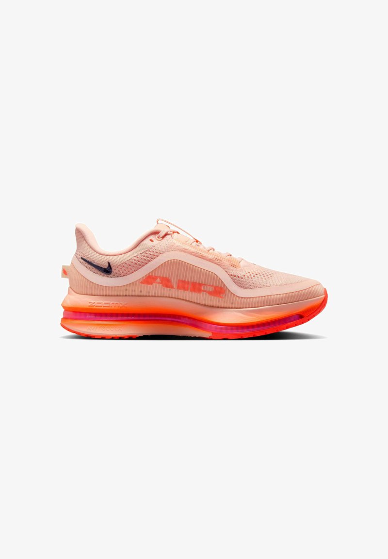 Zapatilla de running Nike Air Zoom en un ligero color coral-rosa con parte superior de malla, suela naranja neón y pequeño swoosh en azul marino oscuro en el talón.