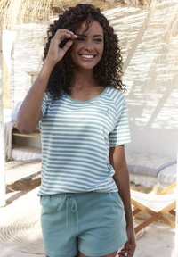 Pruhované zelenobílé tričko s krátkým rukávem, spárované s jednobarevnými zelenými šortkami. Uvolněný střih, bavlněný materiál, s malým detailem "úsměvu".