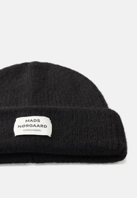 Gorro preto de malha feito de tecido texturizado, apresenta uma aba dobrada com uma etiqueta branca exibindo "MADS NØRGAARD COPENHAGUE."