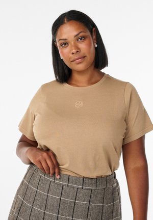 Lysebrun t-shirt lavet af blødt stof, med rund hals og korte ærmer. Forsiden har en subtil broderet logo detalje.