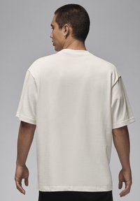 T-shirt di cotone bianco con maniche corte, vestibilità morbida, collo rotondo e texture uniforme, vista dal retro. Nessun motivo o logo visibile.