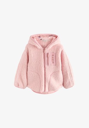 Smilende pige iført en lyserød, blød lynlåsjakke med teksten "BAKER", hvid t-shirt og sorte leggings mod en ensfarvet baggrund.