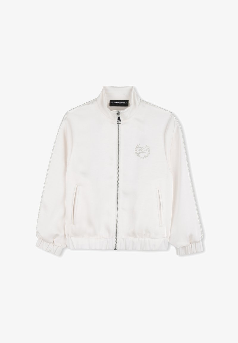 Veste blanche zippée avec col montant, poignets et ourlet élastiques, poches latérales, et logo discret avec couronne de laurier sur la poitrine gauche.