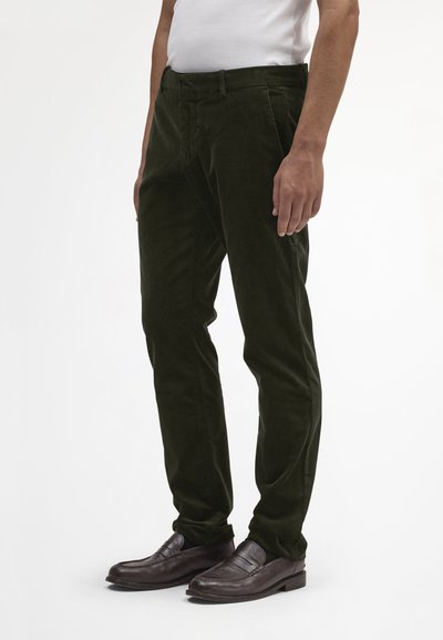 Pantaloni di velluto a coste verde scuro con taglio dritto, caratterizzati da una finitura testurizzata, tasche frontali e indossati con mocassini marroni.
