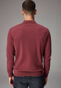 Bordeaux lang�ærmet polo t-shirt med en tætsiddende pasform og ribbede manchetter og kant. Bagfra ses en glat strikket tekstur. Bæres med mørke denim jeans.