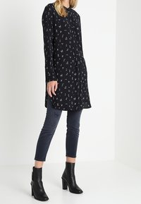 Svart blommig blus med lång ärm och knapplist, kombinerad med mörkblå skinny jeans och svarta klackade ankelstövlar.